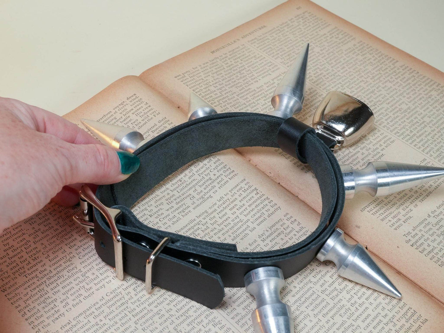 Black leather hucow collar with silver spikes and buckle held over vintage book pages