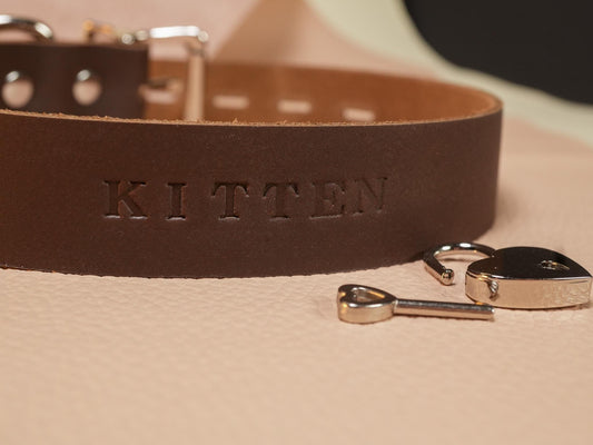 Brown leather collar engraved with kitten and a small lock and key symbolizing a submissive contract