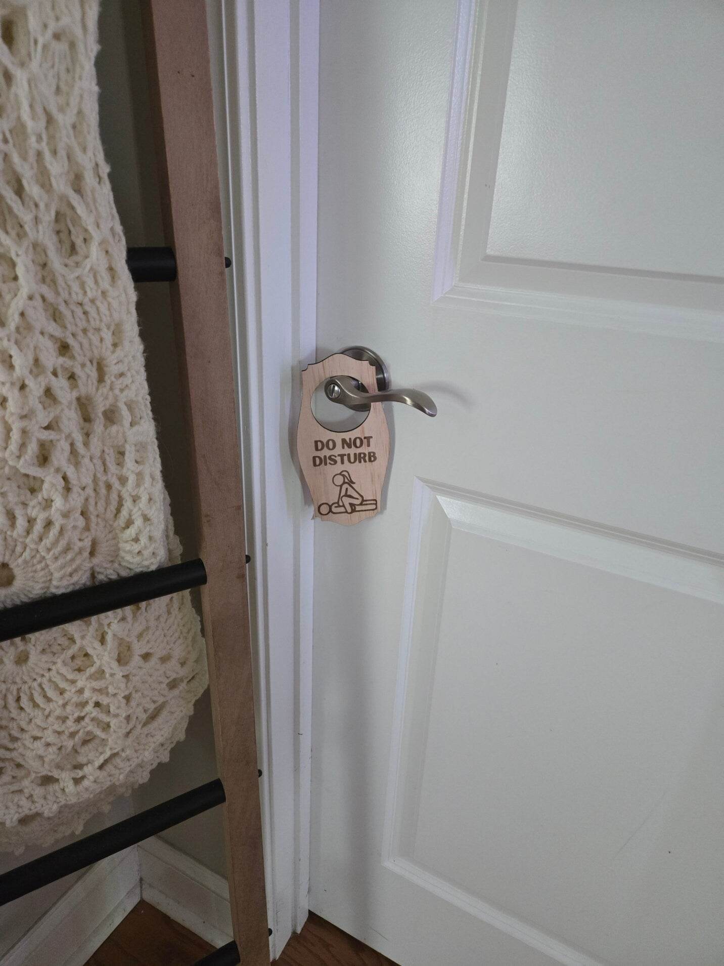 Adult do not disturb sign hanging on silver door handle of a white door in a cozy room
