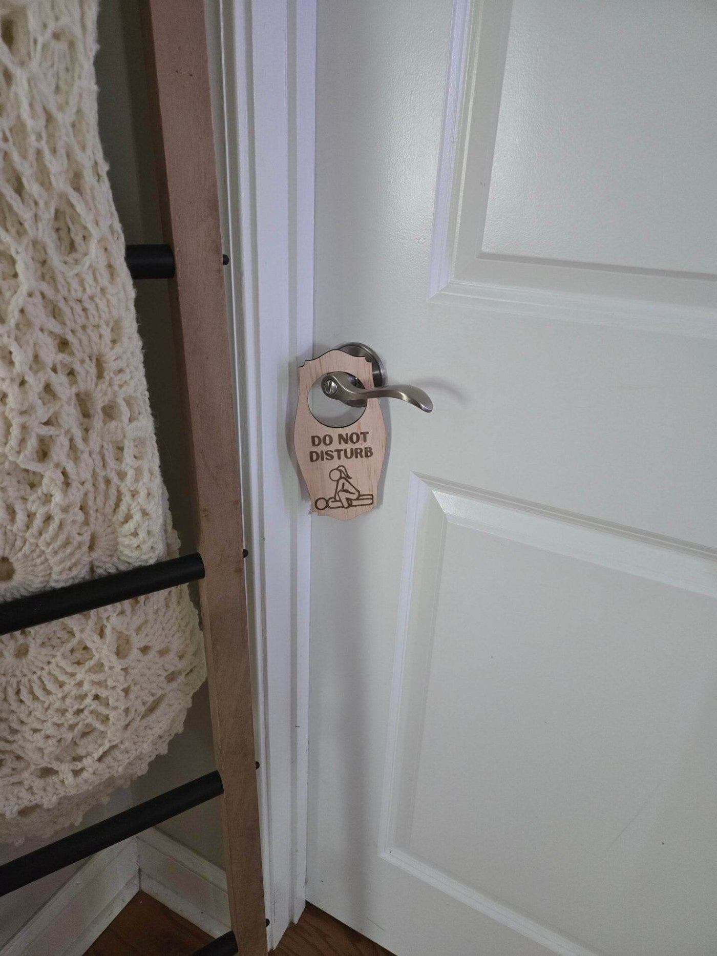 Adult do not disturb sign hanging on silver door handle of a white door in a cozy room