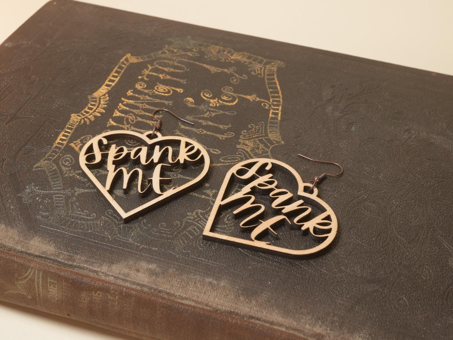 Bound by Dave wooden heart-shaped bdsm earrings with spank me cutout design on vintage book