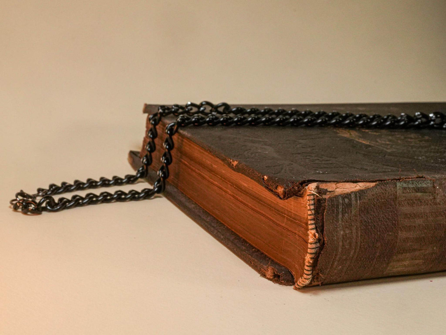 Bound by Dave black chain necklace with Cow Tag pendant draped over old vintage book