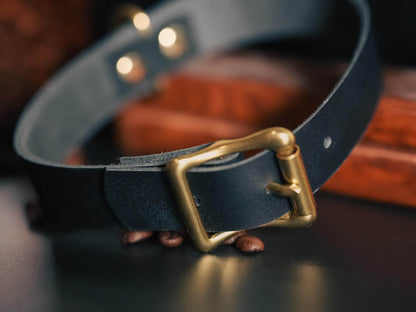 Bound by Dave black leather day collar with brass buckle on dark surface
