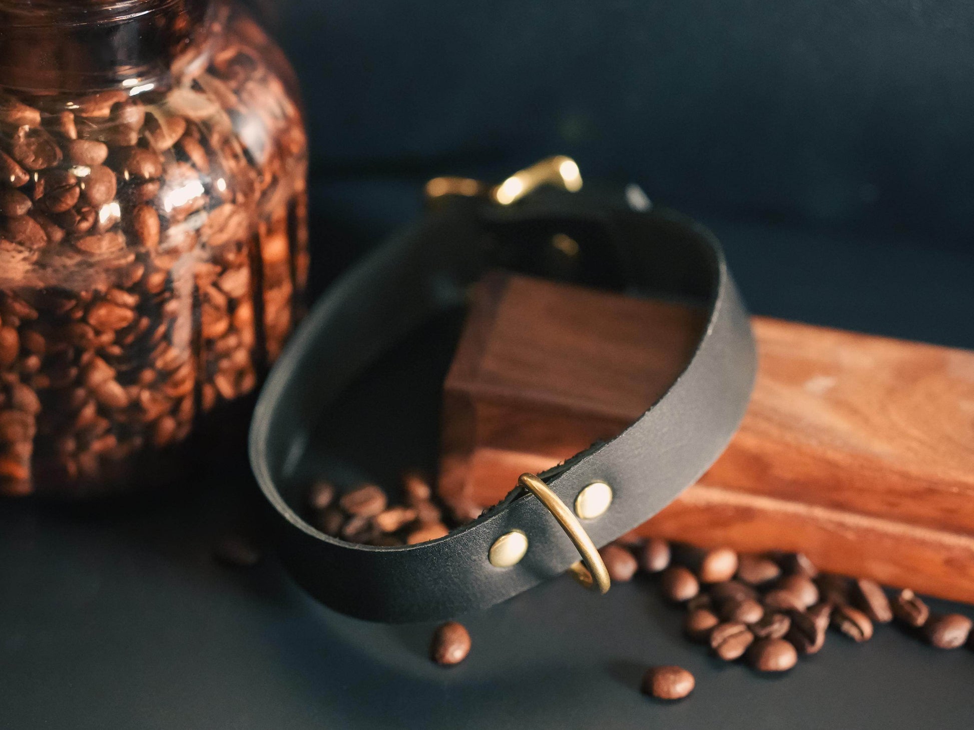 Bound by Dave black leather day collar with brass hardware next to coffee beans and wooden block