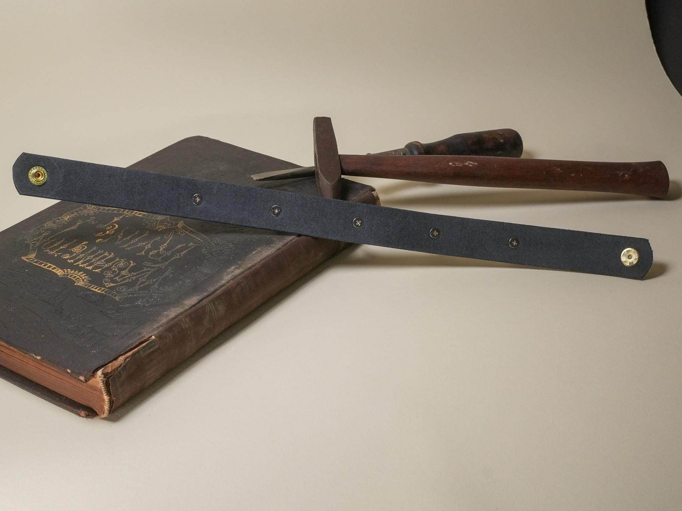 Bound by Dave black leather Goth Choker with metal snap buttons displayed with vintage tools and book