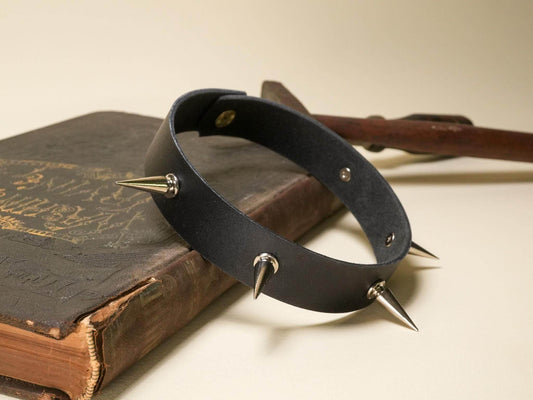 Black leather Goth Choker with silver spikes displayed on an old vintage book