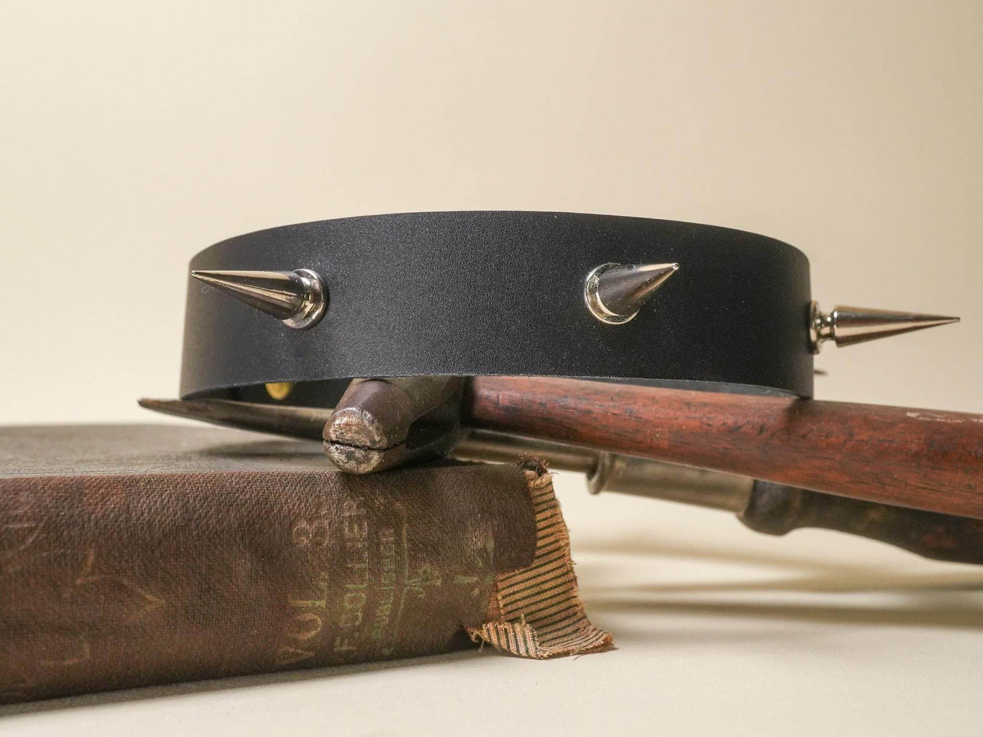 Black Goth Choker with silver spikes resting on vintage books and a wooden object