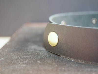 Bound by Dave black leather Goth Choker with gold-tone metal stud detail on brown surface