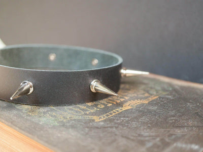Black leather Goth Choker with silver metal spikes by Bound by Dave resting on a vintage book