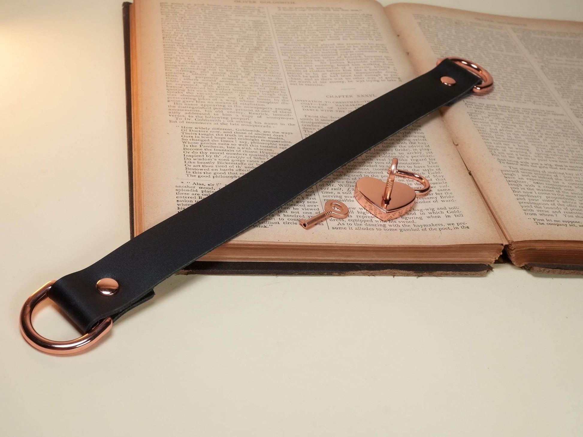 Bound by Dave black leather strap with rose gold heart lock and key on vintage book pages