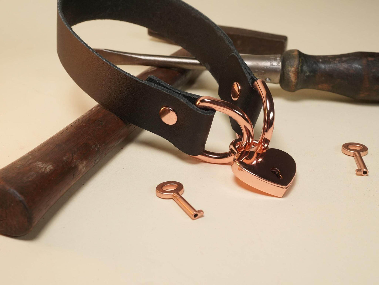 Bound by Dave black leather collar with rose gold Heart Lock and matching keys on beige background