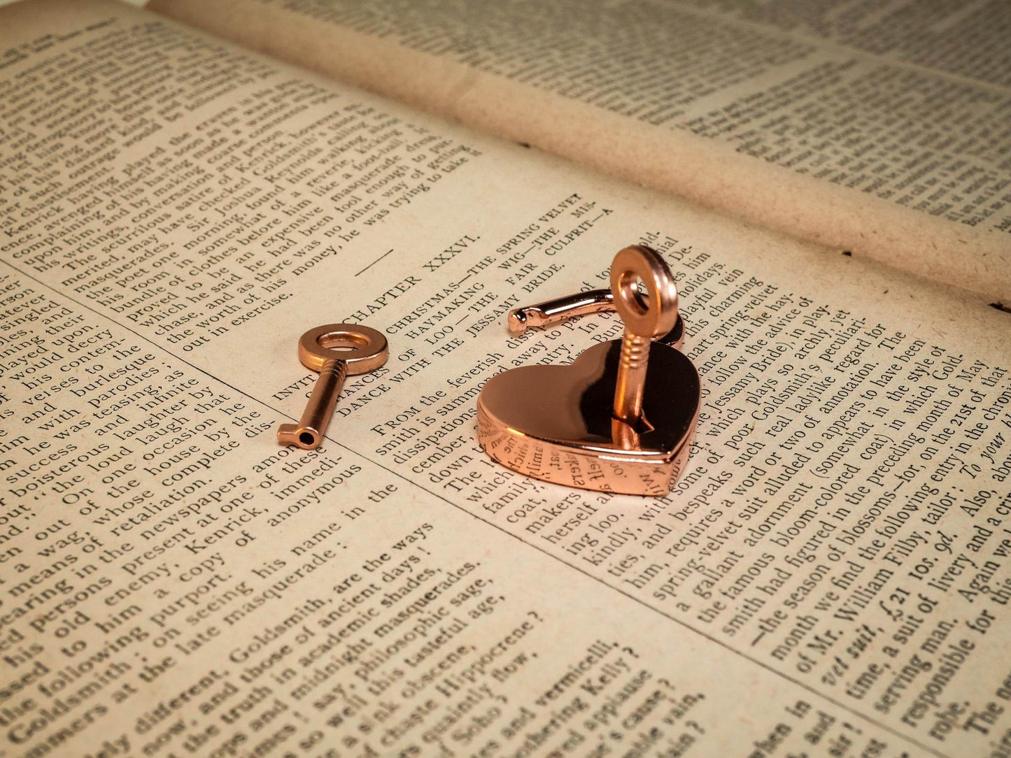 Heart Lock and two keys in rose gold placed on an open vintage book page