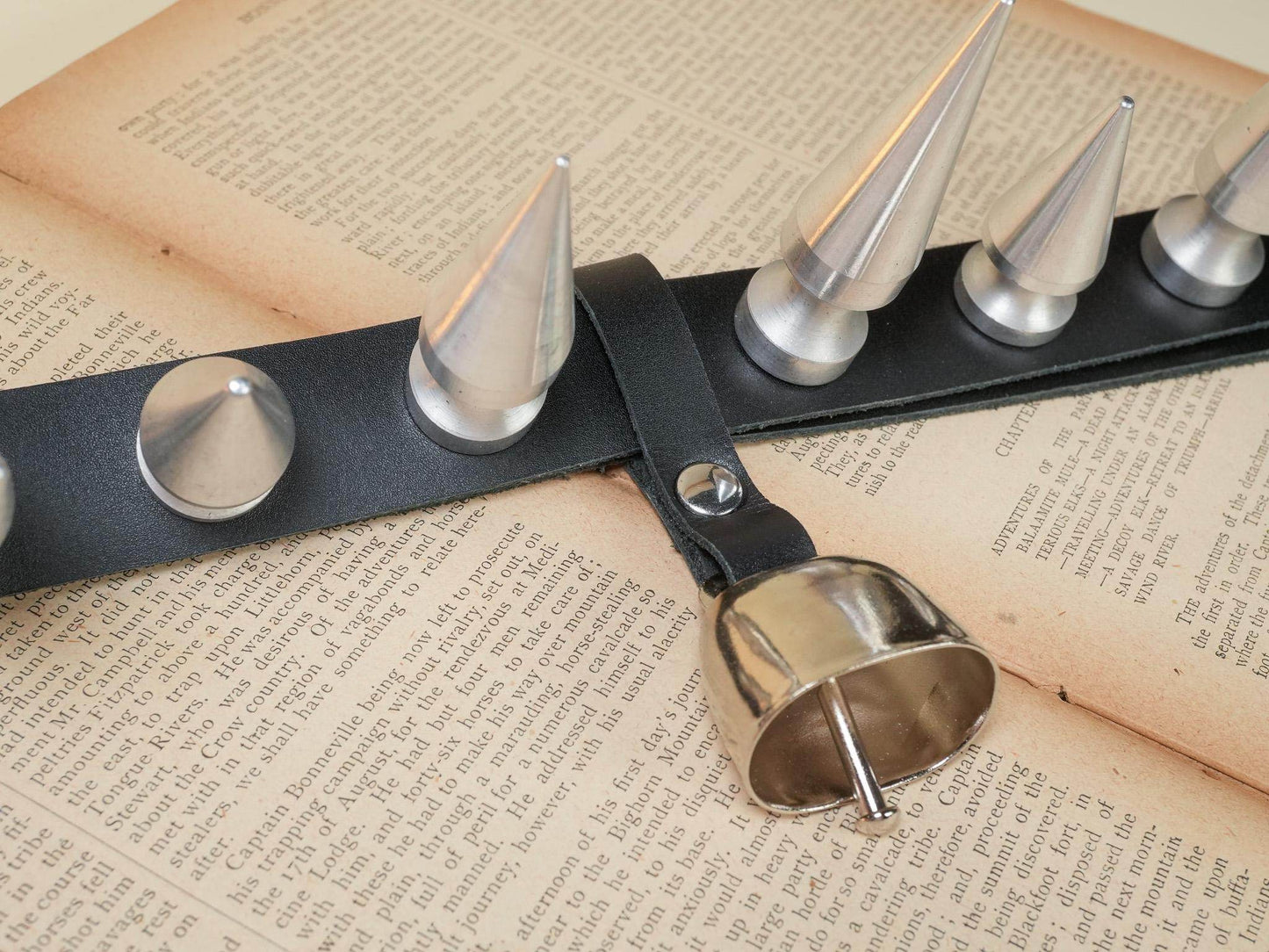 Bound by Dave black leather hucow collar with metal spikes and attached bell on open book pages