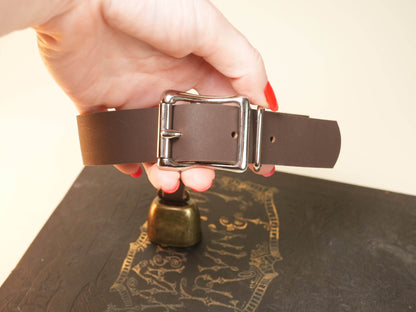 Hand holding Bound by Dave brown leather Hucow Collar with metal buckle and bell