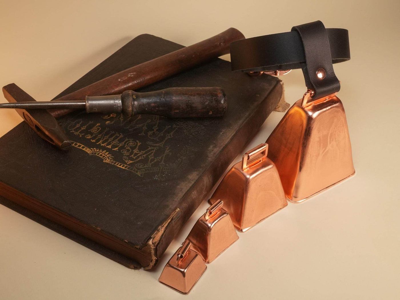 Bound by Dave Hucow Collar with copper bells and black leather strap displayed on vintage book with tools