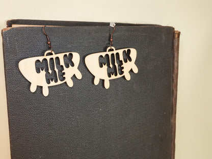 Hucow Earrings by Bound by Dave shaped like udders with milk me text in black and white design