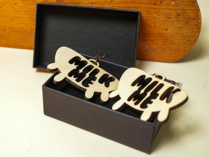 Wooden Hucow Earrings with milk me design in black text inside black jewelry box by Bound by Dave
