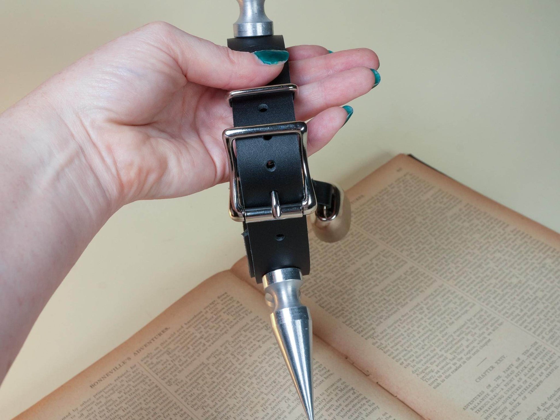 Bound by Dave black leather hucow collar with metal cone and buckle held over an open book