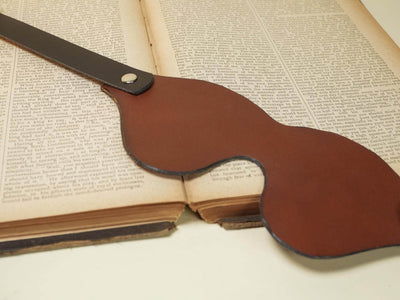 Brown Leather Blindfold from Bound by Dave resting on an open vintage book