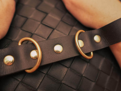 Bound by Dave black leather hand cuffs with gold rivets and rings on woven leather background