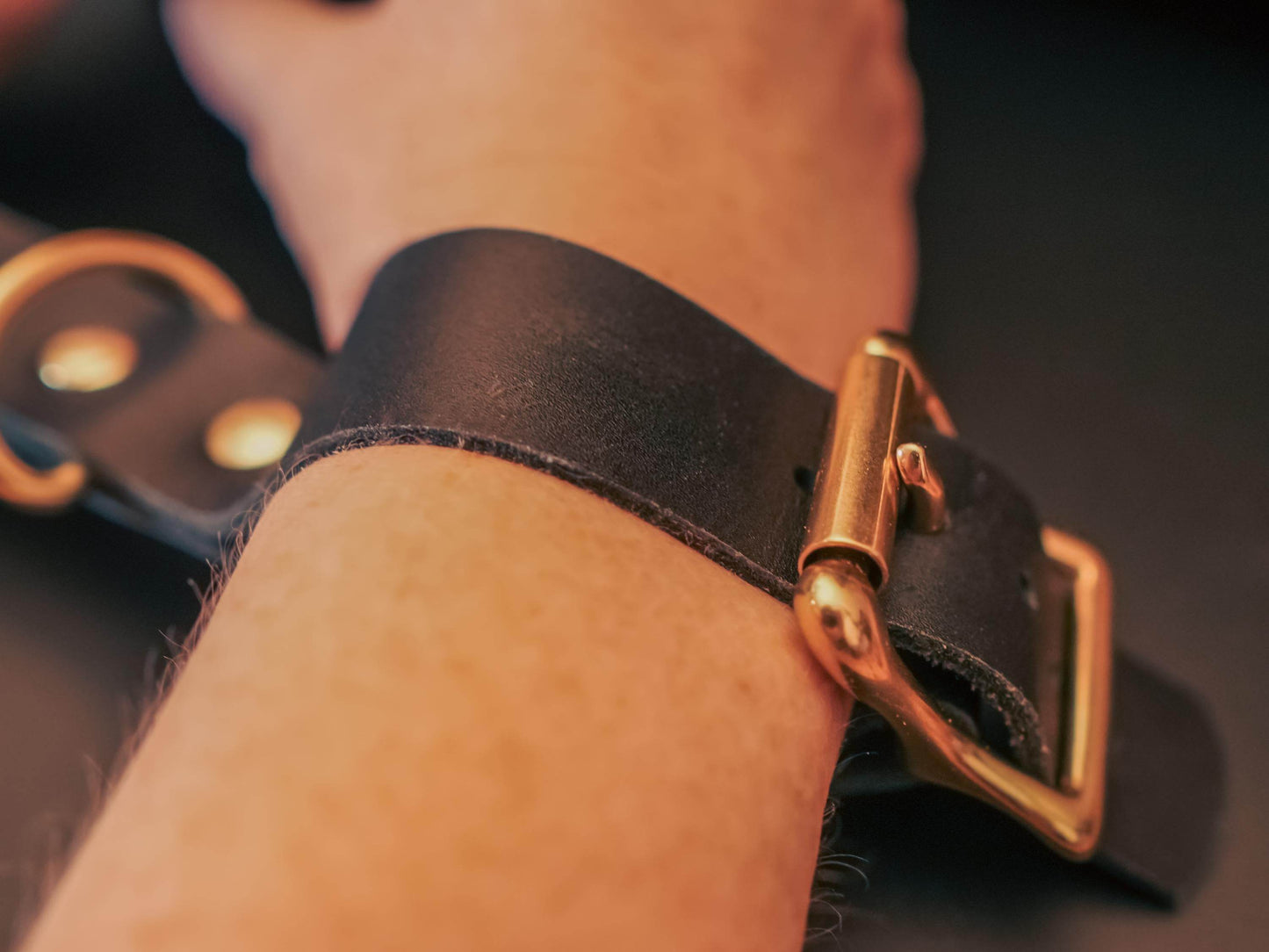 Leather hand cuffs by Bound by Dave fastened around a wrist with a brass buckle