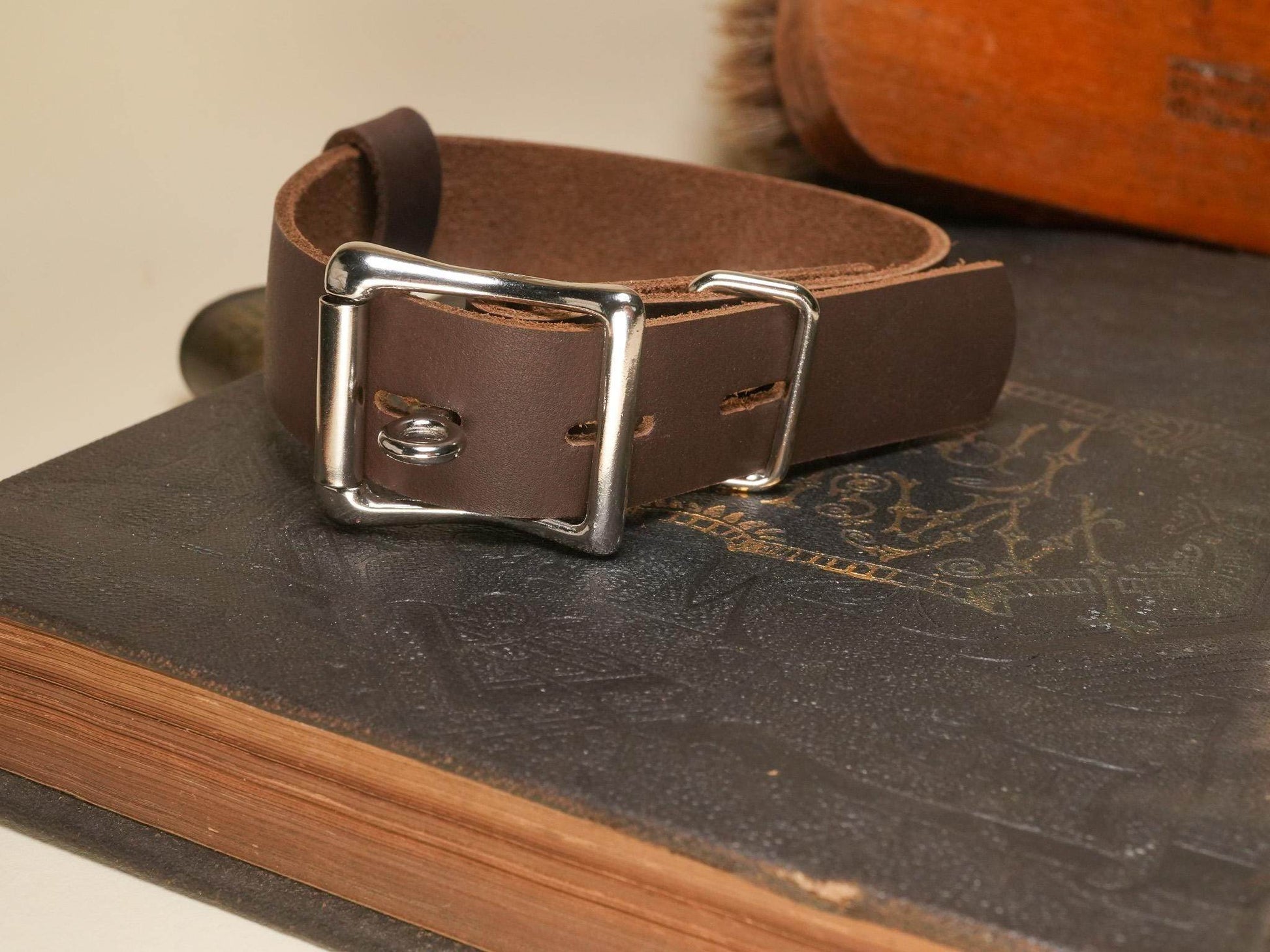 Locking Hucow Collar in brown leather with silver buckle by Bound by Dave on a vintage book