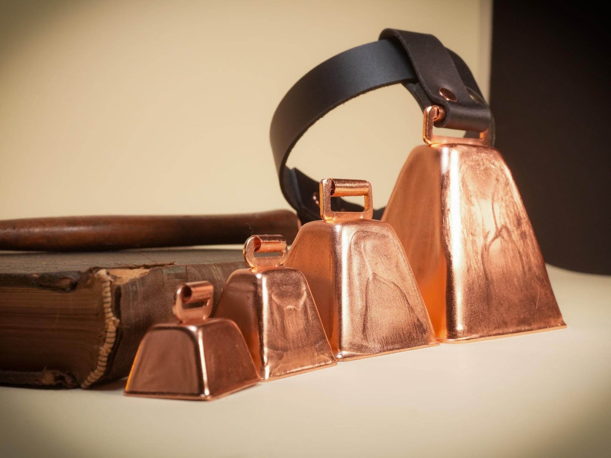 Locking hucow collar with four copper cowbells of varying sizes and black leather strap