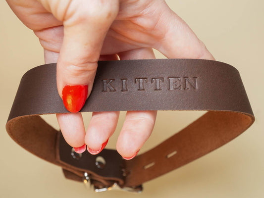 Bound by Dave brown leather Locking Sub Collar with KITTTEN embossed held by hand with red nail polish