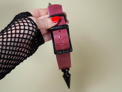 Hand holding burgundy leather Rave Choker with black buckle and spike detail