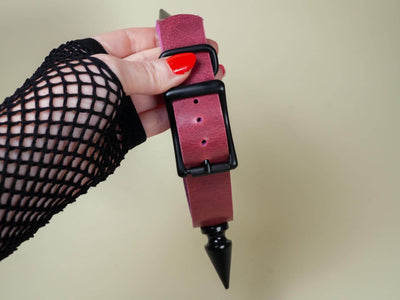 Hand holding burgundy leather Rave Choker with black buckle and spike detail