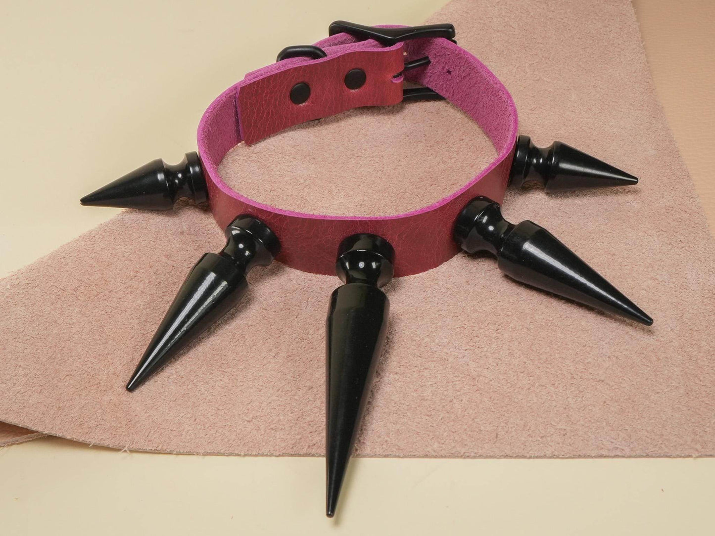Bound by Dave Rave Choker with black spikes and pink strap on beige textured surface