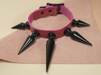 Bound by Dave Rave Choker with black spikes and pink strap on beige textured surface