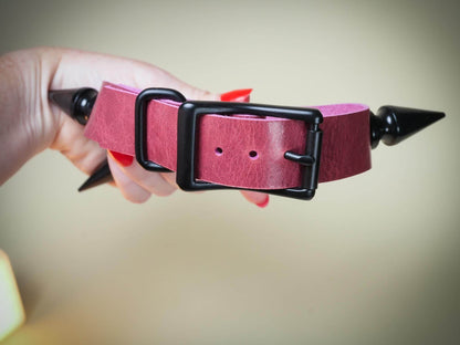 Bound by Dave pink leather Rave Choker with black metal buckle and spikes held in hand