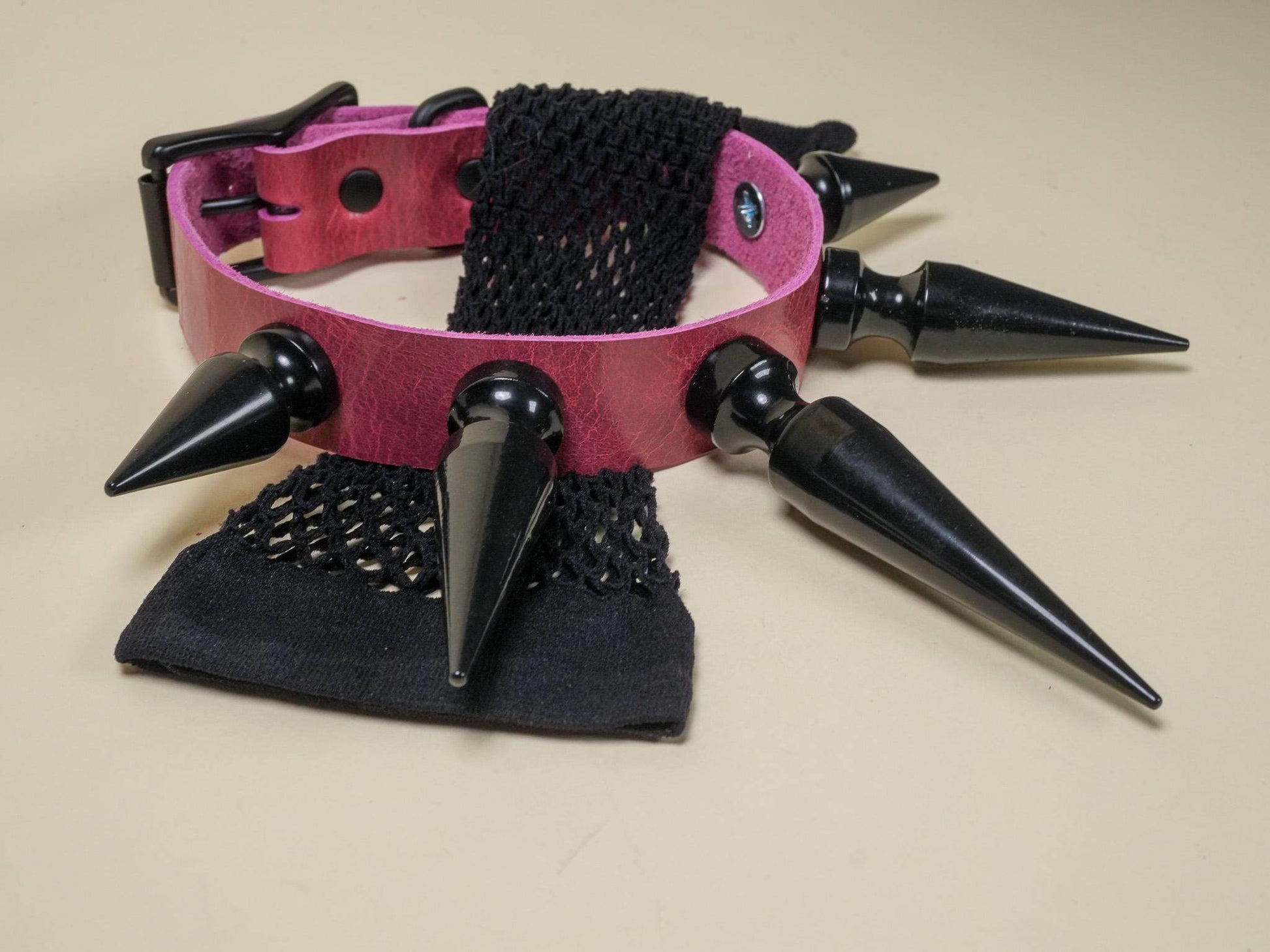 Bound by Dave Rave Choker with large black spikes and pink leather strap on beige background