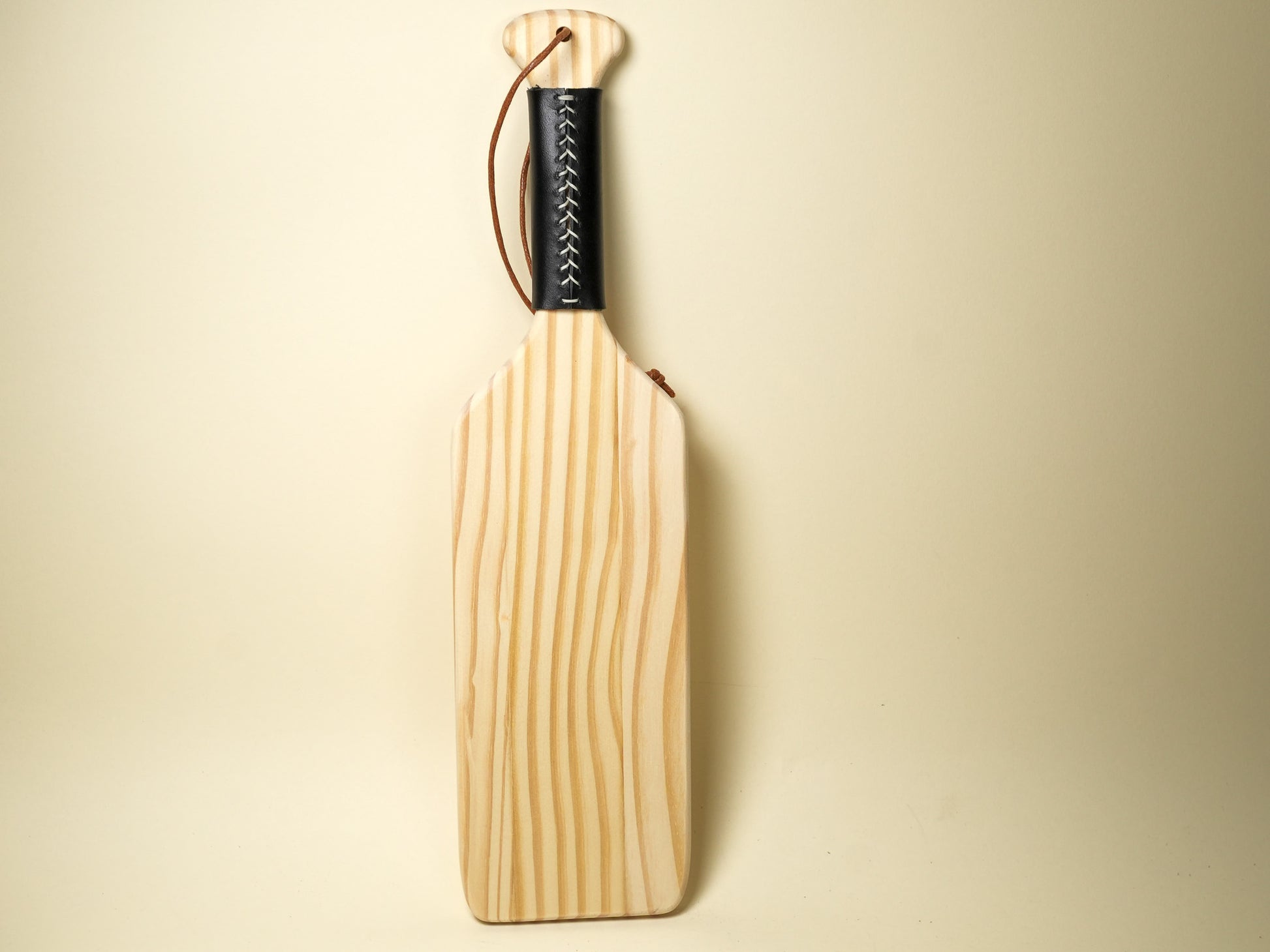 Wooden Spanking Paddle with black wrapped handle and leather wrist strap by Bound by Dave