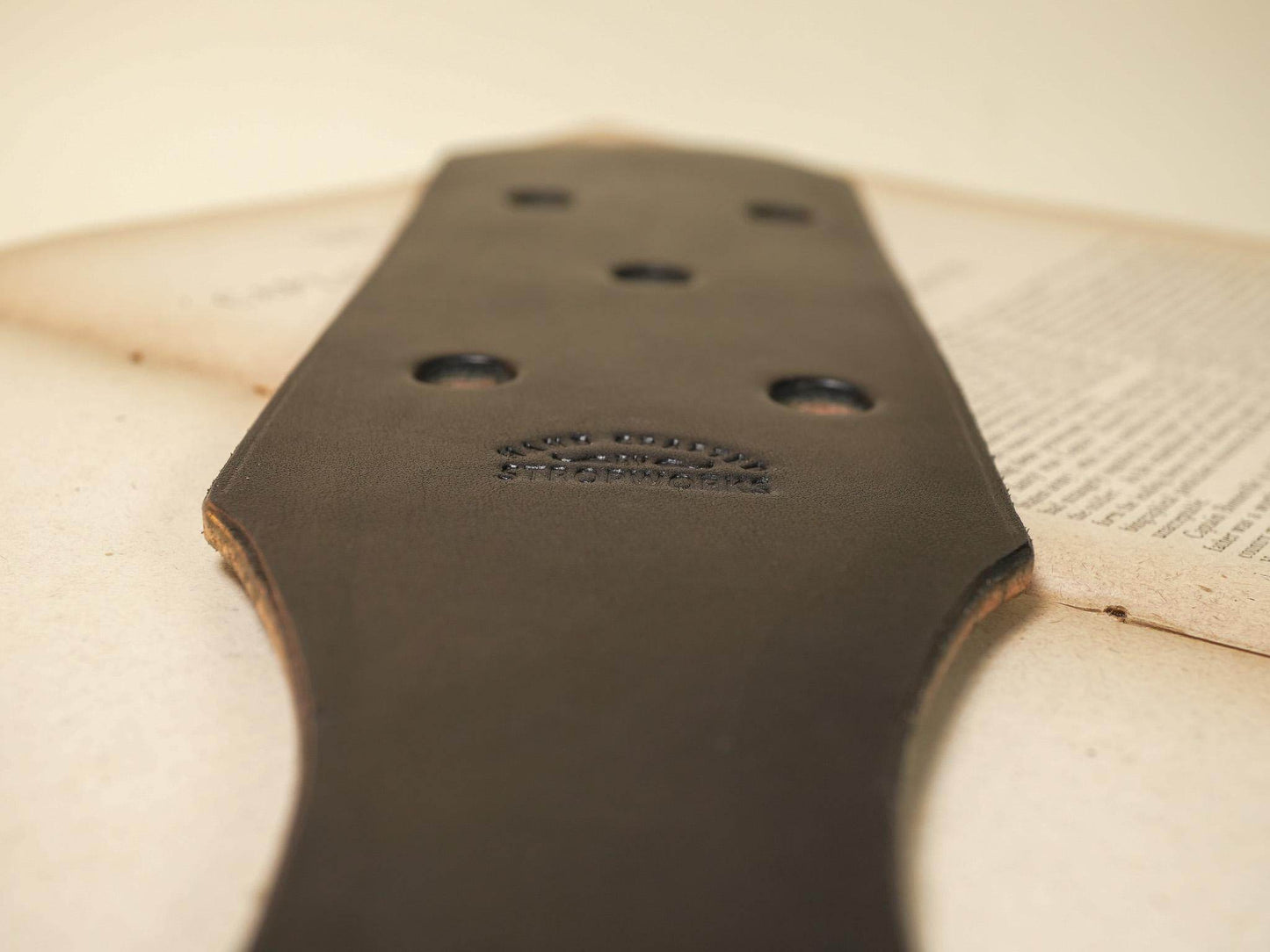 Bound by Dave leather paddle with multiple Leather Paddle Holes on textured surface