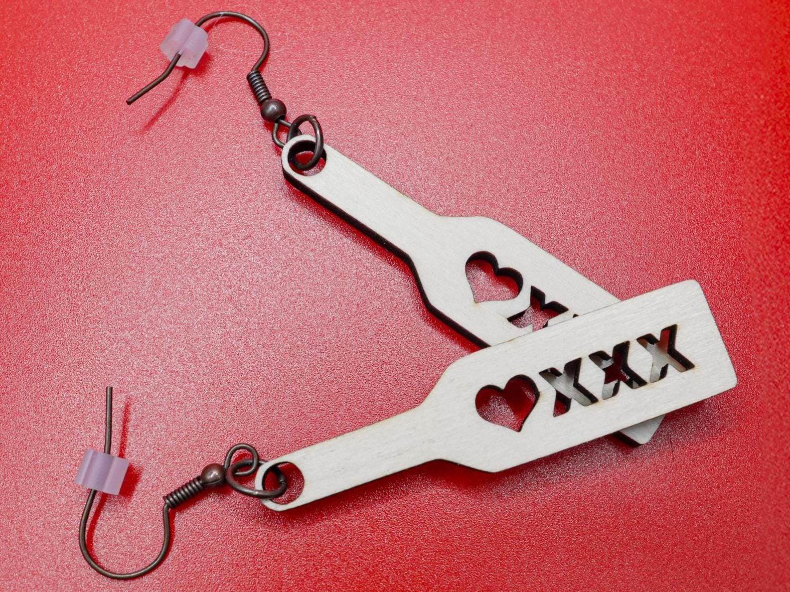 Bound by Dave wood spanking paddle earrings with heart and xxx cutouts on red background