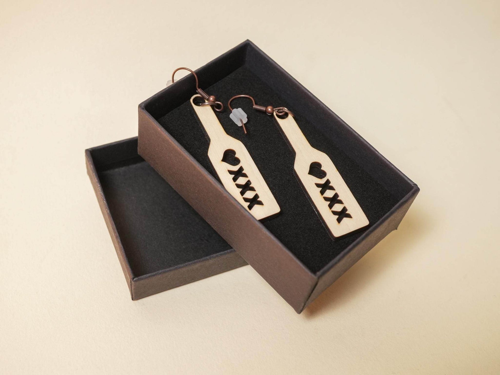 Wood spanking paddle earrings with heart and XXX cutout design in a black gift box by Bound by Dave